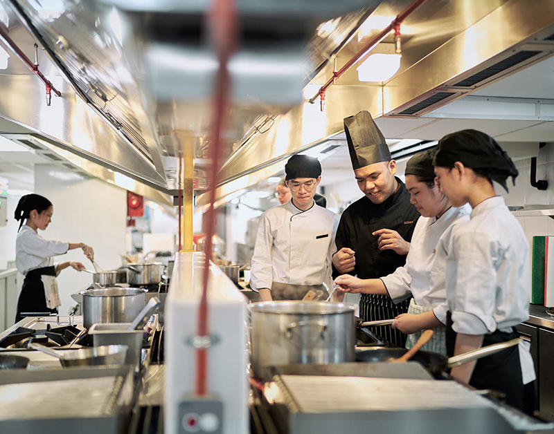 A lecturer teaching students on culinary arts.