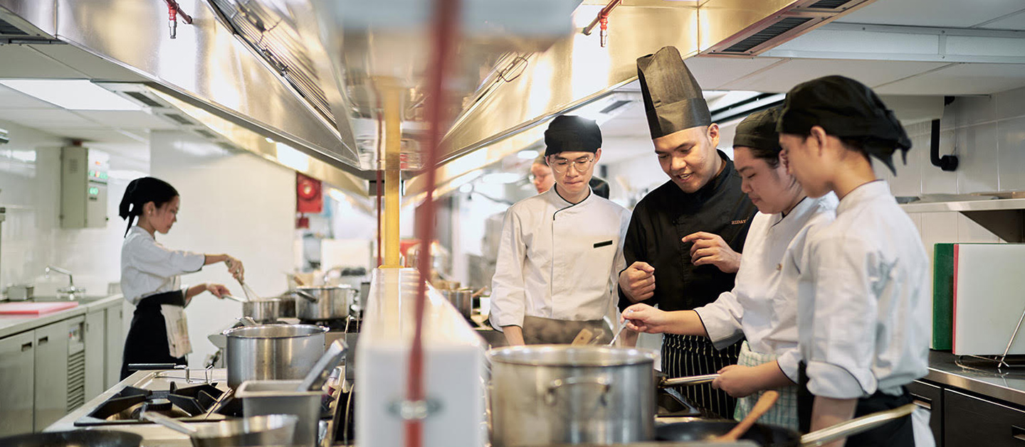 A lecturer teaching students on culinary arts.