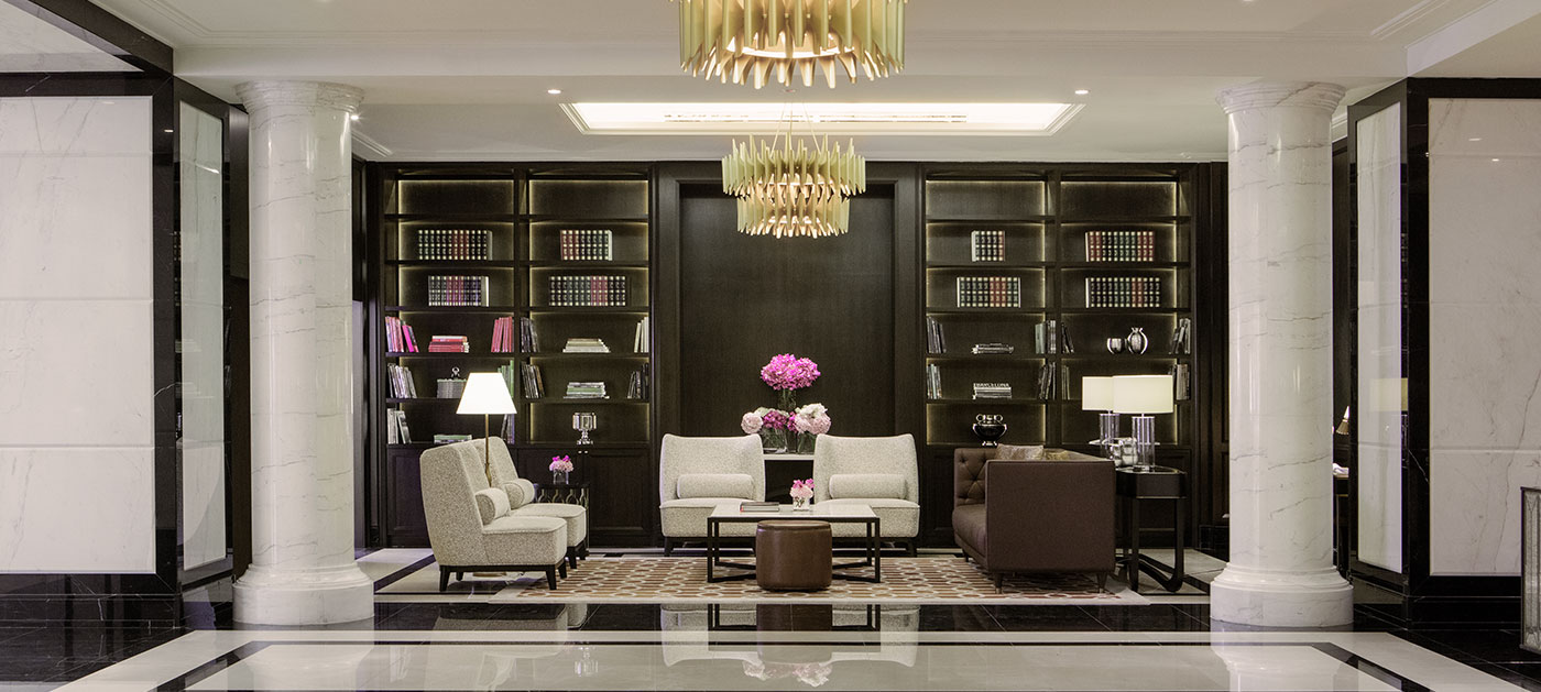 A hall with sofa and coffee table and a shelf filled with books at the back.